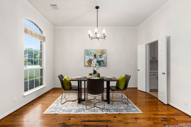 dining area featuring visible vents, crown molding, wood finished floors, baseboards, and a notable chandelier