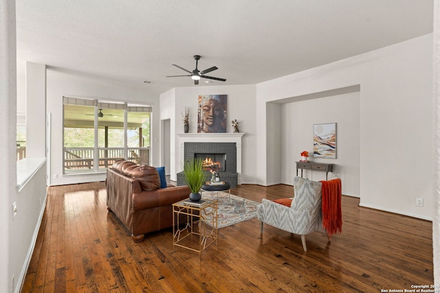 living area with a fireplace, a ceiling fan, baseboards, visible vents, and hardwood / wood-style flooring
