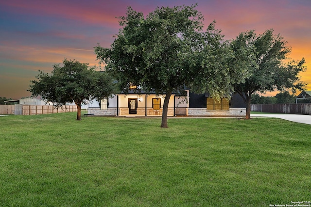 exterior space with a lawn, fence, and stone siding