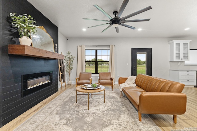 living area featuring light wood-style floors, a glass covered fireplace, and recessed lighting
