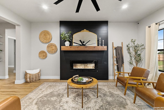 living area featuring ceiling fan, a fireplace, recessed lighting, baseboards, and wood finished floors