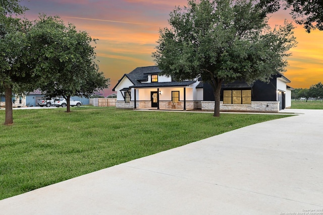 modern farmhouse style home featuring a lawn, stone siding, and stucco siding