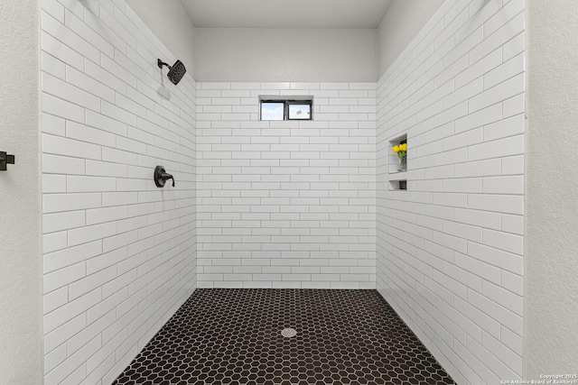 full bathroom with a textured wall and a tile shower