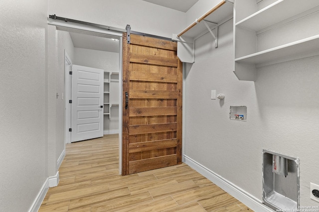 laundry area with washer hookup, baseboards, and light wood finished floors