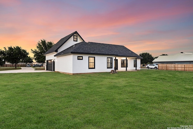 back of property featuring a lawn, fence, concrete driveway, and a garage