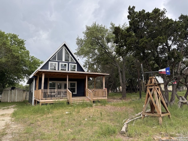 back of property with fence and covered porch