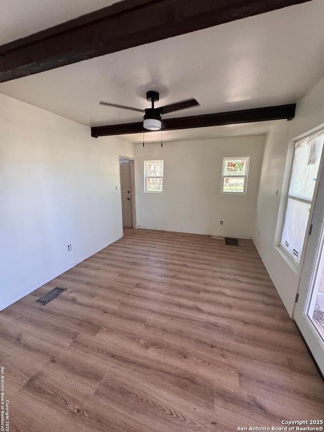 unfurnished room with light wood-style floors, a ceiling fan, a wealth of natural light, and visible vents