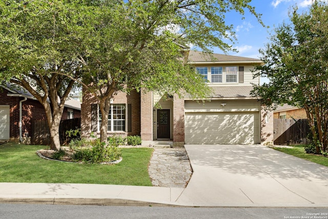 view of front of home featuring a front lawn, fence, brick siding, an attached garage, and driveway