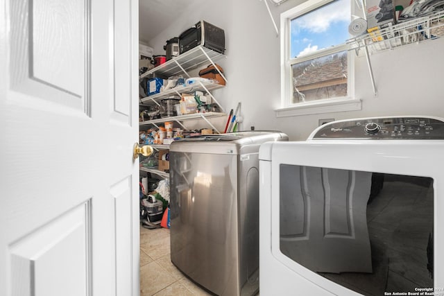 washroom with light tile patterned floors, laundry area, and washing machine and clothes dryer