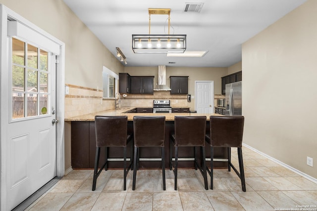 kitchen featuring decorative backsplash, visible vents, a sink, a peninsula, and stainless steel appliances