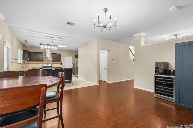 dining room with visible vents, wood finished floors, baseboards, beverage cooler, and a notable chandelier