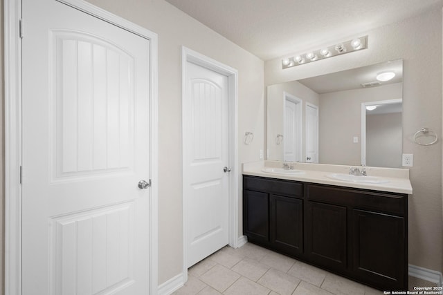 full bathroom featuring tile patterned flooring, a sink, baseboards, and double vanity