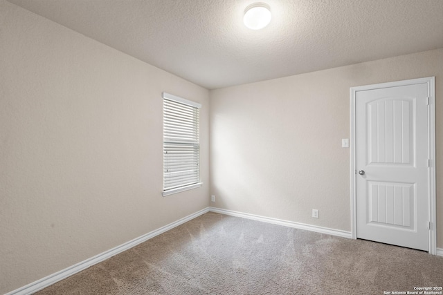 carpeted spare room with a textured ceiling and baseboards