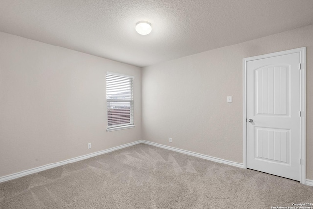 carpeted spare room with baseboards and a textured ceiling
