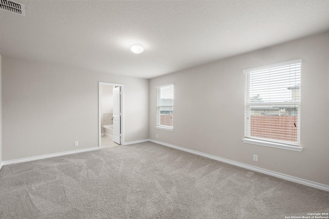 carpeted spare room featuring visible vents, a textured ceiling, and baseboards