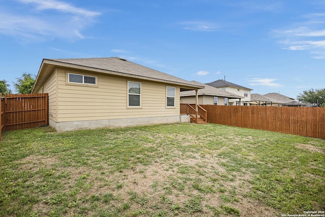 rear view of house featuring a fenced backyard and a yard