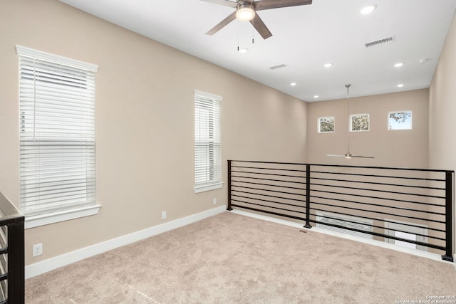 spare room with carpet flooring, a ceiling fan, baseboards, and visible vents