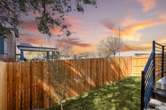 yard at dusk featuring a fenced backyard