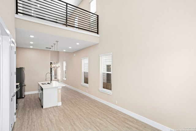 kitchen with plenty of natural light, freestanding refrigerator, light wood-style flooring, and a center island with sink