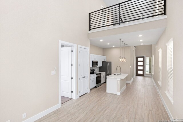 kitchen featuring a sink, light countertops, a high ceiling, stainless steel appliances, and white cabinetry