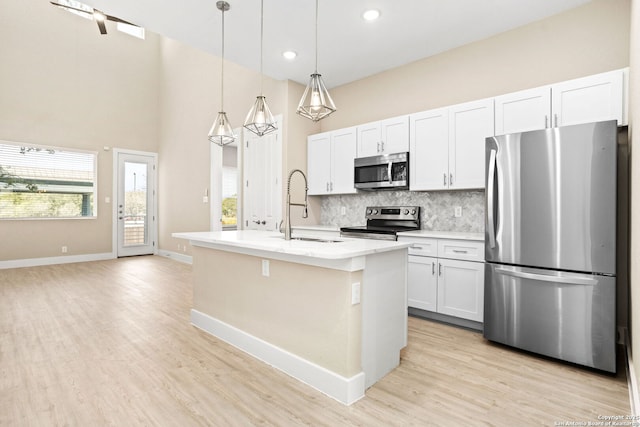 kitchen featuring tasteful backsplash, light wood-type flooring, a sink, light countertops, and stainless steel appliances
