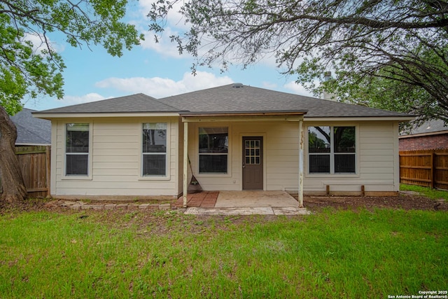 rear view of property featuring fence private yard, a shingled roof, a patio area, and a yard