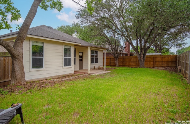 exterior space featuring a yard, a patio, a shingled roof, and a fenced backyard