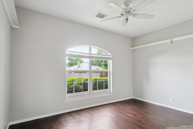 empty room with baseboards, visible vents, ceiling fan, and dark wood-type flooring