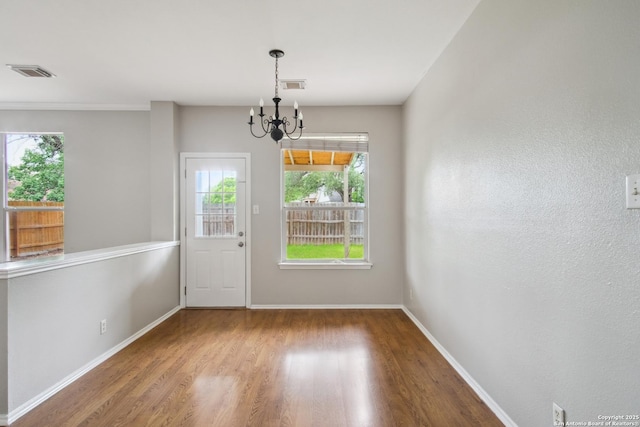 doorway with a notable chandelier, wood finished floors, and visible vents