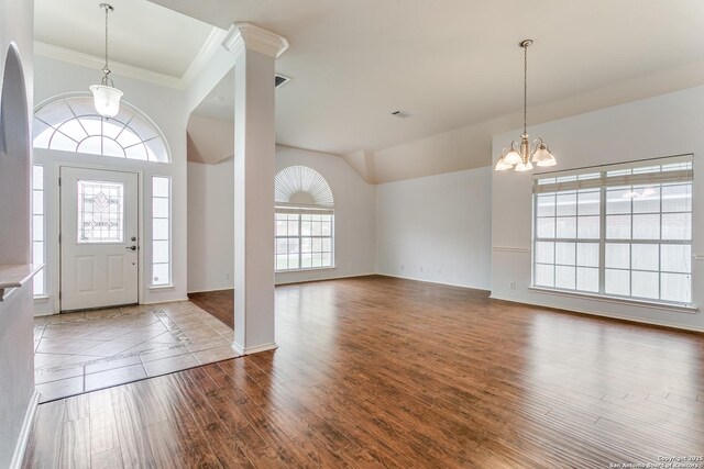 foyer featuring visible vents, ornamental molding, wood finished floors, baseboards, and a chandelier