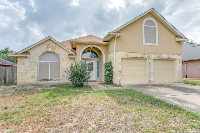 mediterranean / spanish-style home with fence, a front yard, stucco siding, an attached garage, and driveway