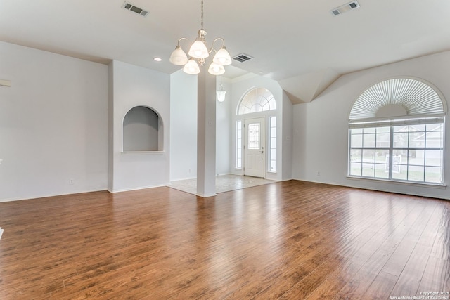 unfurnished living room with a notable chandelier, wood finished floors, and visible vents