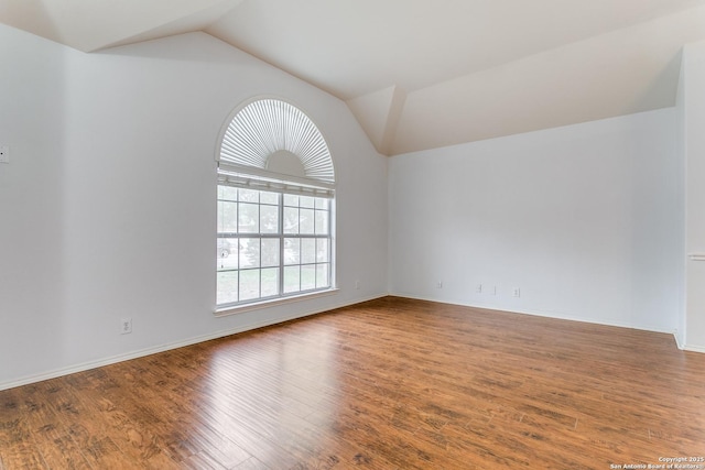 spare room with baseboards, wood finished floors, and lofted ceiling