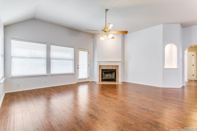 unfurnished living room featuring a ceiling fan, a healthy amount of sunlight, wood finished floors, and a tile fireplace