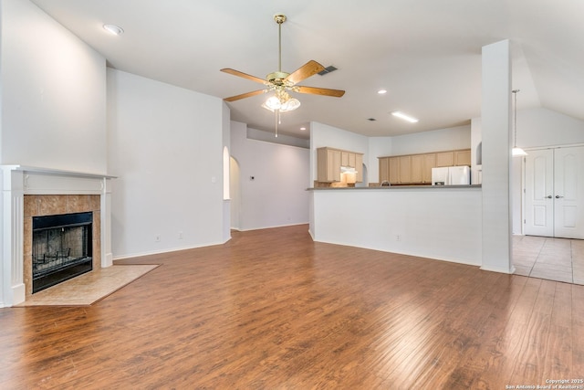 unfurnished living room with ceiling fan, recessed lighting, wood finished floors, lofted ceiling, and a tile fireplace