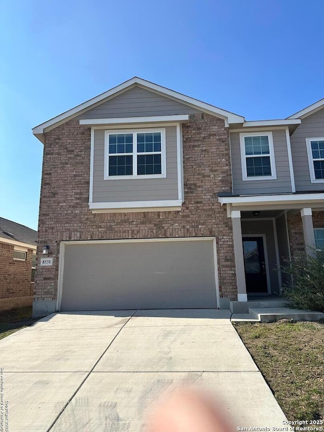 view of front of house featuring brick siding, an attached garage, and driveway