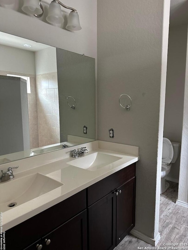 bathroom with double vanity, a sink, wood finished floors, and toilet