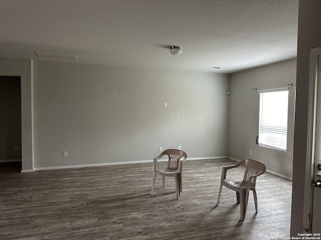unfurnished room with baseboards, wood finished floors, and visible vents