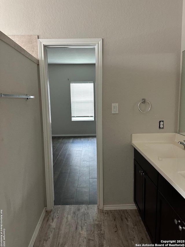 bathroom with baseboards, wood finished floors, and vanity