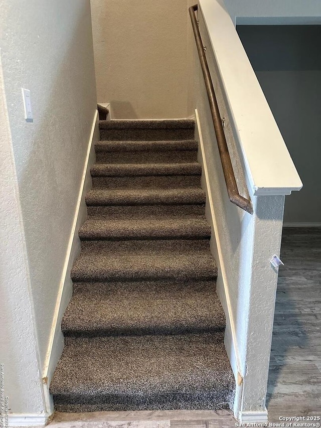 stairway with baseboards, a textured wall, and wood finished floors