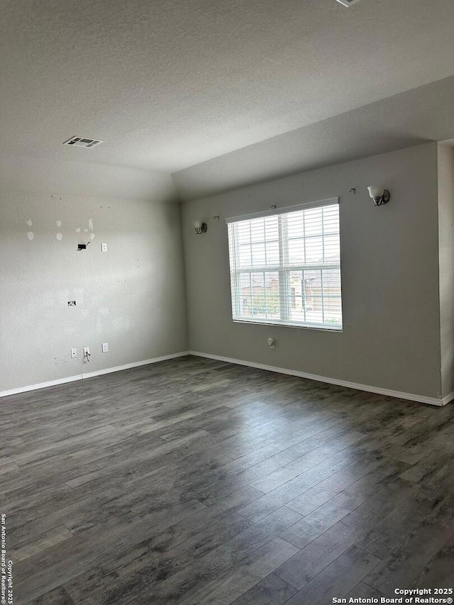 spare room featuring baseboards, dark wood finished floors, and lofted ceiling