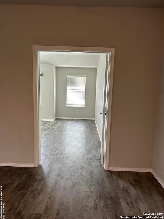 unfurnished room featuring baseboards and dark wood finished floors