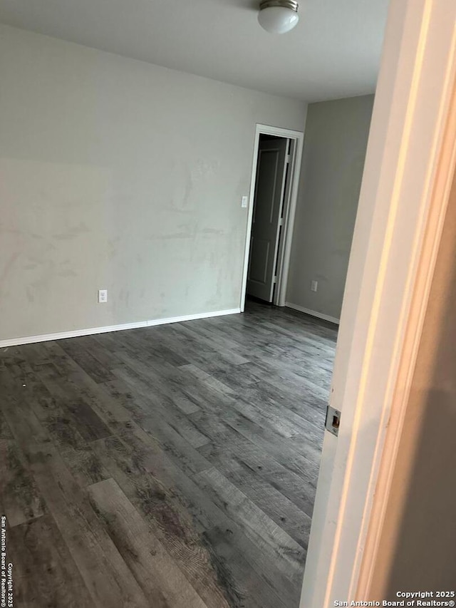 empty room with baseboards and dark wood finished floors