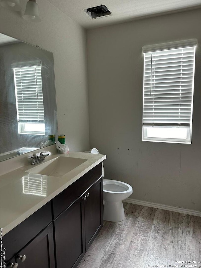 half bathroom featuring vanity, wood finished floors, and toilet