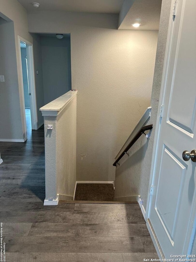 stairway with baseboards, a textured wall, and wood finished floors