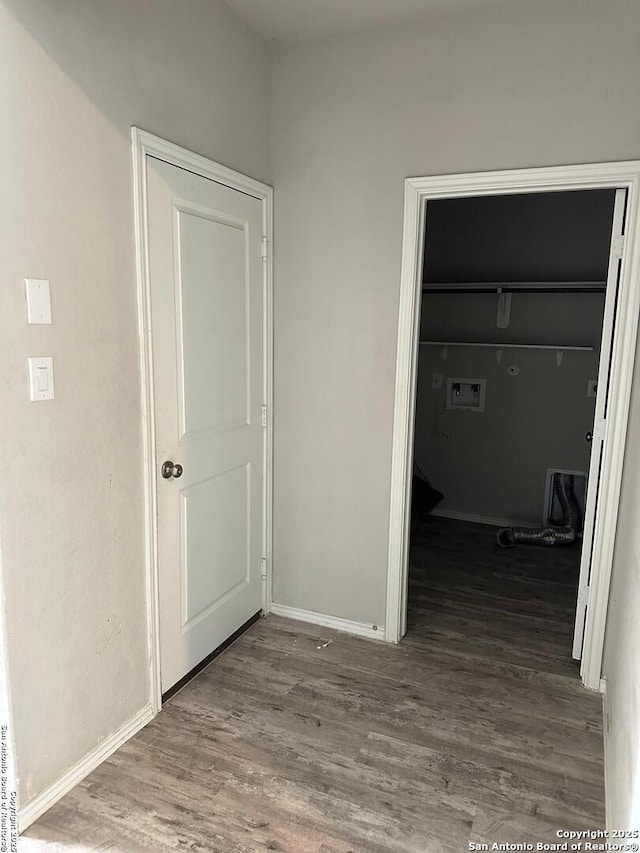 unfurnished bedroom with a walk in closet, baseboards, a closet, and wood finished floors