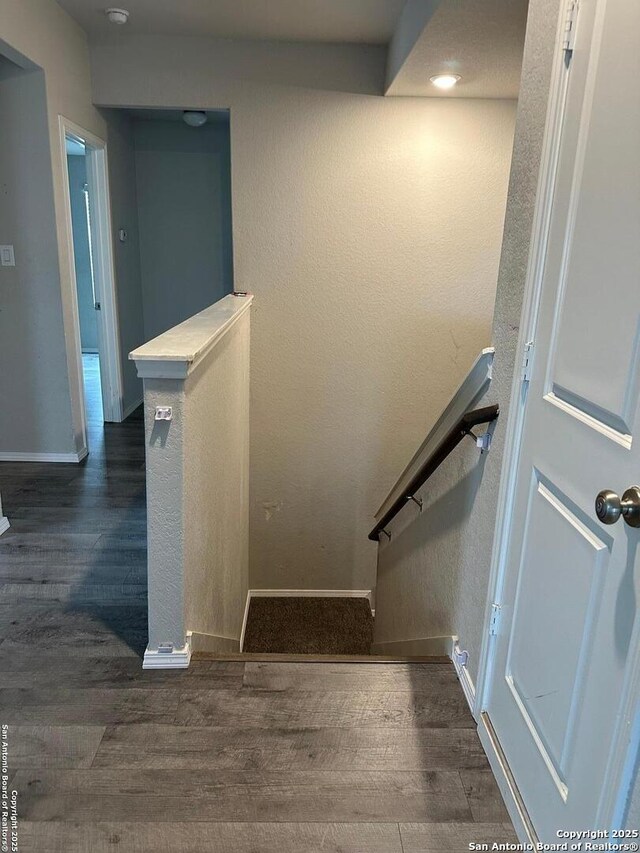 stairway with baseboards, a textured wall, and wood finished floors