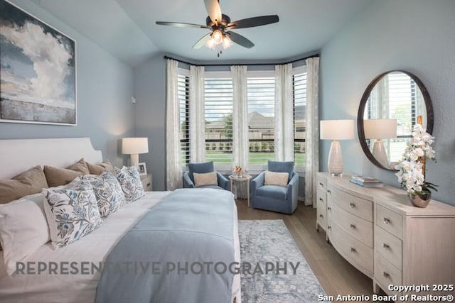 bedroom with a ceiling fan, lofted ceiling, and wood finished floors