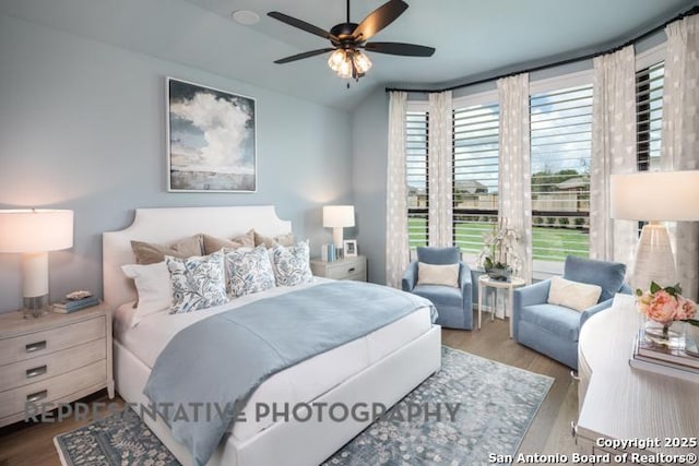 bedroom with ceiling fan, wood finished floors, and lofted ceiling