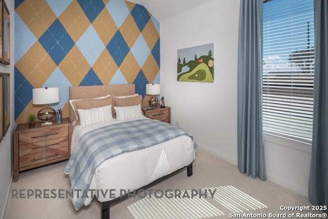 bedroom featuring baseboards, an accent wall, and carpet flooring